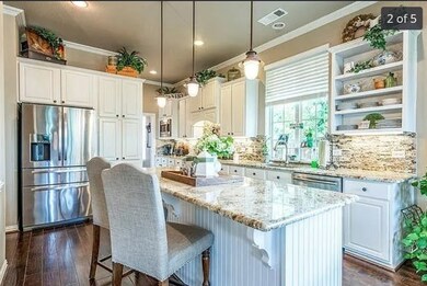Kitchen featuring white cabinetry, decorative light fixtures, a kitchen breakfast bar, light stone countertops, and appliances with stainless steel finishes