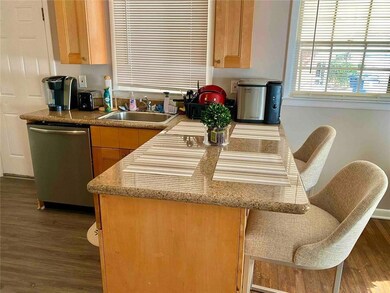 Kitchen featuring dishwasher, wood finished floors, a kitchen bar, and light brown cabinetry