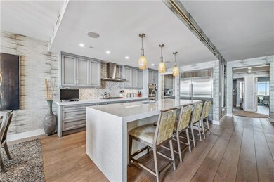 Kitchen featuring gray cabinetry, a kitchen bar, light stone countertops, and stainless steel appliances