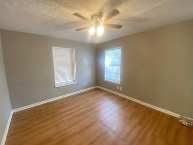 Unfurnished room featuring a textured ceiling, wood finished floors, and ceiling fan