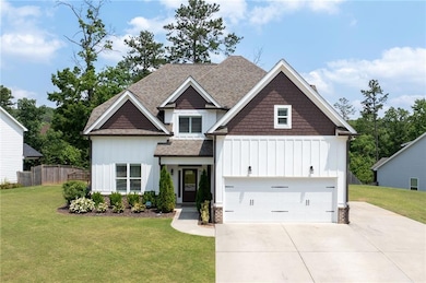 Craftsman-style home featuring board and batten siding, roof with shingles, driveway, and a garage