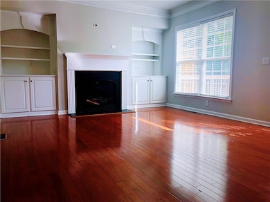 Unfurnished living room with built in features, hardwood / wood-style floors, baseboards, and a fireplace with flush hearth