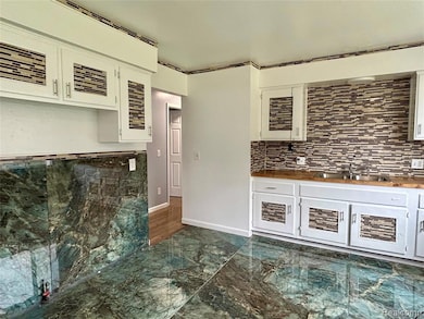 Kitchen with white cabinets, dark marble finish floors, and decorative backsplash