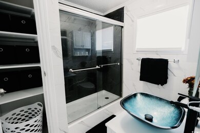 Bathroom with a shower stall, a textured ceiling, and crown molding
