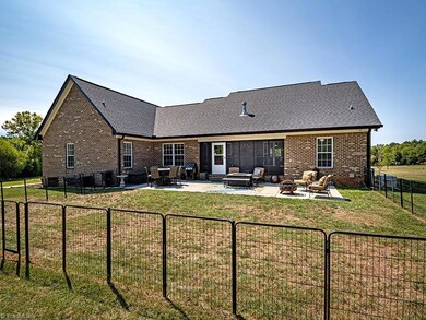 View of the back of the home showing screened porch, large patio area and flat backyard.