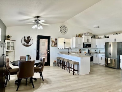 Kitchen with stainless steel appliances, light wood finished floors, a breakfast bar area, a peninsula, and lofted ceiling