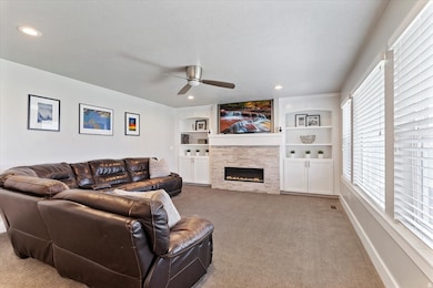 Living area featuring built in shelves, a tiled fireplace, carpet floors, ceiling fan, and recessed lighting