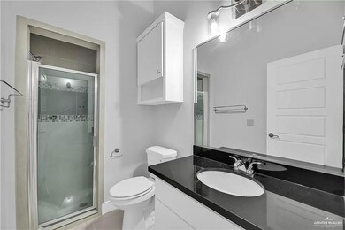 Bathroom featuring a shower with shower door, vanity, and toilet
