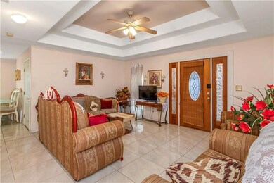 Living room with light tile flooring, ceiling fan, and a raised ceiling