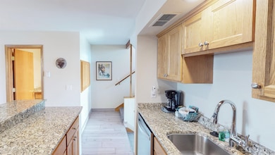 Kitchen featuring light stone countertops, light wood finished floors, dishwasher, and light brown cabinetry