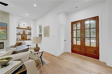 Entrance foyer featuring light wood-style floors, a fireplace, recessed lighting, and french doors