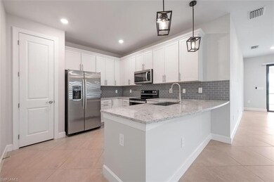 Kitchen featuring stainless steel appliances, a sink, light tile patterned floors, a peninsula, and recessed lighting