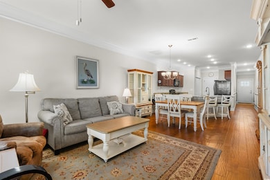 Living room featuring crown molding, wood finished floors, a ceiling fan, a chandelier, and recessed lighting