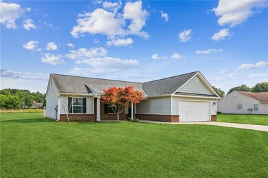 View of front of house with brick siding, an attached garage, a front lawn, and concrete driveway