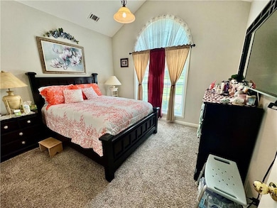 Bedroom with light colored carpet and high vaulted ceiling