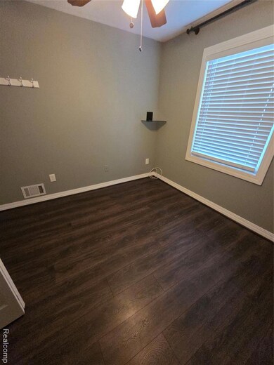 Empty room with ceiling fan and dark wood finished floors