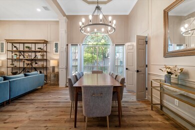Dining room with an inviting chandelier, ornate columns, LVP / wood-type flooring, and crown molding