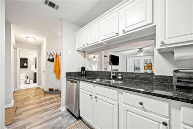 Kitchen featuring white cabinetry, sink, stainless steel dishwasher, ceiling fan, and a textured ceiling