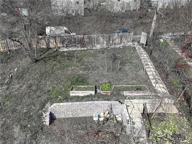 View from the the back of the Home of the cement steps to the Alley and parking, retaining wall, trees, plant beds and Wood Slat Fence with Gate.
