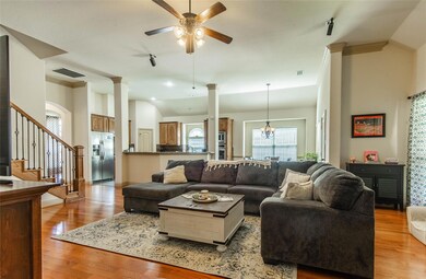 Living room with hardwood floors, decorative columns, lofted ceiling, and ceiling fan