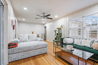 Living room featuring hardwood / wood-style flooring, ceiling fan, and a textured ceiling