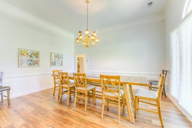 Dining space featuring ornamental molding, a chandelier, wood finished floors, and wainscoting