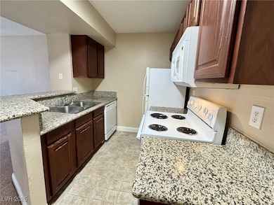 Kitchen featuring white appliances, a sink, basebo