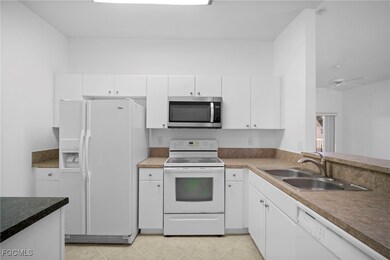 Kitchen featuring white appliances, white cabinetry, ceiling fan, and light tile patterned flooring