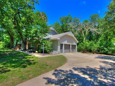 View of front of property with stone siding, concrete driveway, a garage, and a front lawn