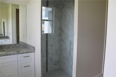 Bathroom with vanity and a marble finish shower