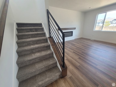 Staircase with a glass covered fireplace and wood finished floors