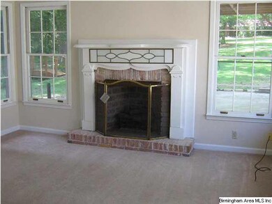 Den with gas logs and backyard view of flower gard