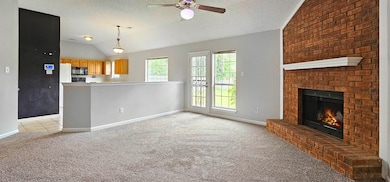 Unfurnished living room with light carpet, a ceiling fan, lofted ceiling, baseboards, and a brick fireplace