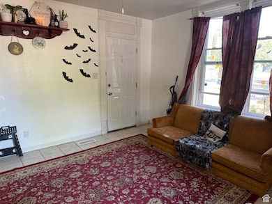 Living room with visible vents, baseboards, and light tile patterned floors