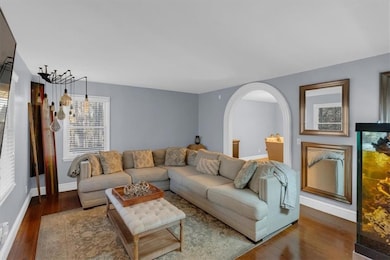 Living area with a wealth of natural light, arched walkways, dark wood finished floors, and baseboards