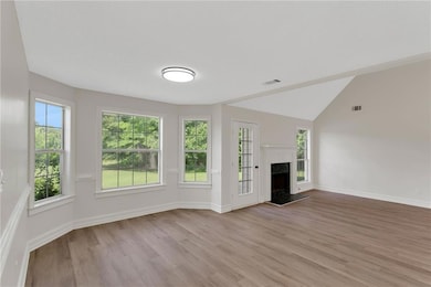 Unfurnished living room with light wood-style flooring, plenty of natural light, baseboards, and a premium fireplace