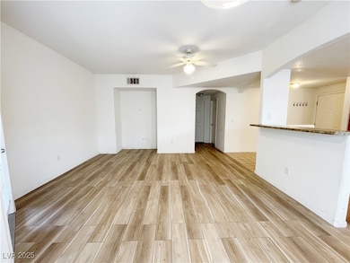 Empty room with arched walkways, ceiling fan, and