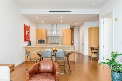 Kitchen featuring backsplash, a peninsula, light brown cabinets, light countertops, and modern cabinets