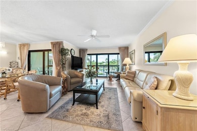 Living room featuring a ceiling fan, crown molding, a textured ceiling, and light tile patterned floors