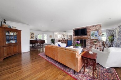 Living room with wood finished floors, a fireplace, and ornamental molding