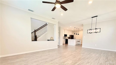 Unfurnished living room with light wood-style flooring, crown molding, recessed lighting, stairway, and ceiling fan