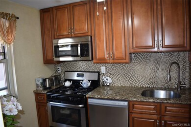 Kitchen featuring stainless steel appliances, tasteful backsplash, dark stone counters, and brown cabinets