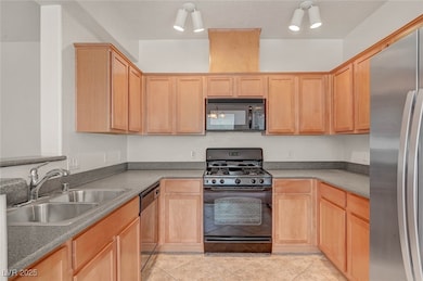 Kitchen featuring black appliances, light tile patterned flooring, and light brown cabinets