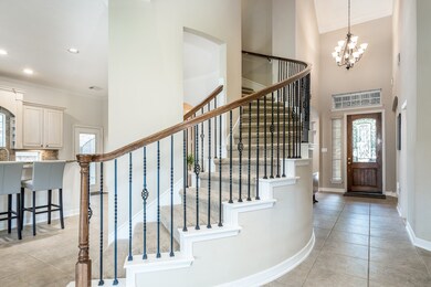 Stunning curved staircase has wrought iron balusters.