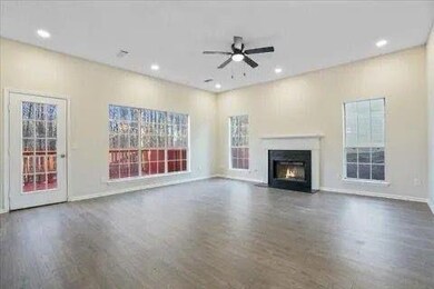 Living room with a fireplace with flush hearth, a ceiling fan, wood finished floors, and plenty of natural light