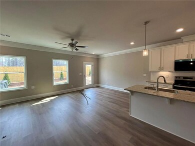 Kitchen with appliances with stainless steel finishes, island with single bowl ss sink, granite countertops, white cabinetry, decorative backsplash, traverse lights, and trash can pull cabinet.