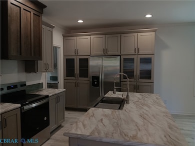 Kitchen with appliances with stainless steel finishes, ornamental molding, light wood-style floors, recessed lighting, and a center island with sink