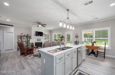 Kitchen with stainless steel dishwasher, plenty of natural light, a fireplace, light countertops, and crown molding