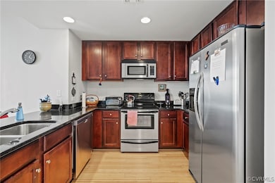 Kitchen featuring dark stone counters, light hardw