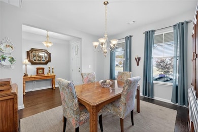 Dining area with dark wood-style floors and a chandelier